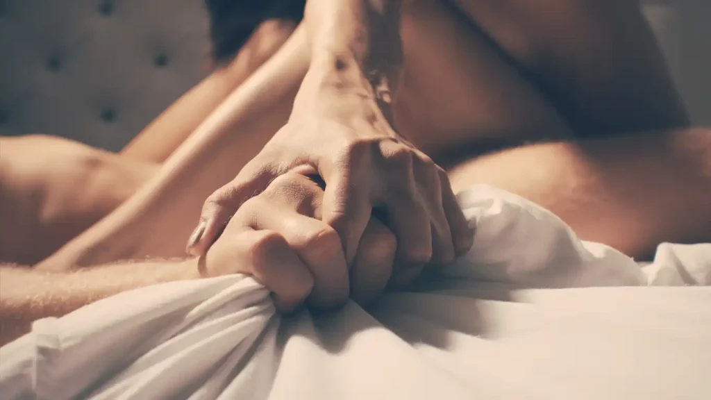 Hands held together symbolizing intimacy and overcoming sexual performance anxiety through connection.